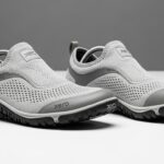 A pair of light grey slip-on athletic shoes with mesh uppers, rubber soles, and "Xero Shoes" branding offers all-day comfort and walking excellence, set against a plain grey and white background.